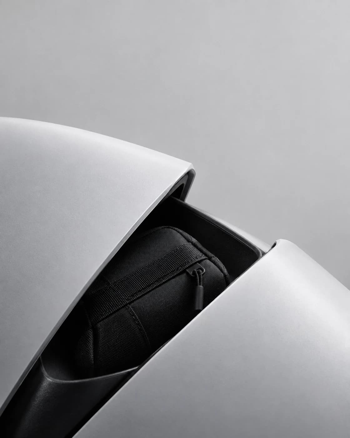 Black fabric pouch revealed between asymmetric matte white shell panels.