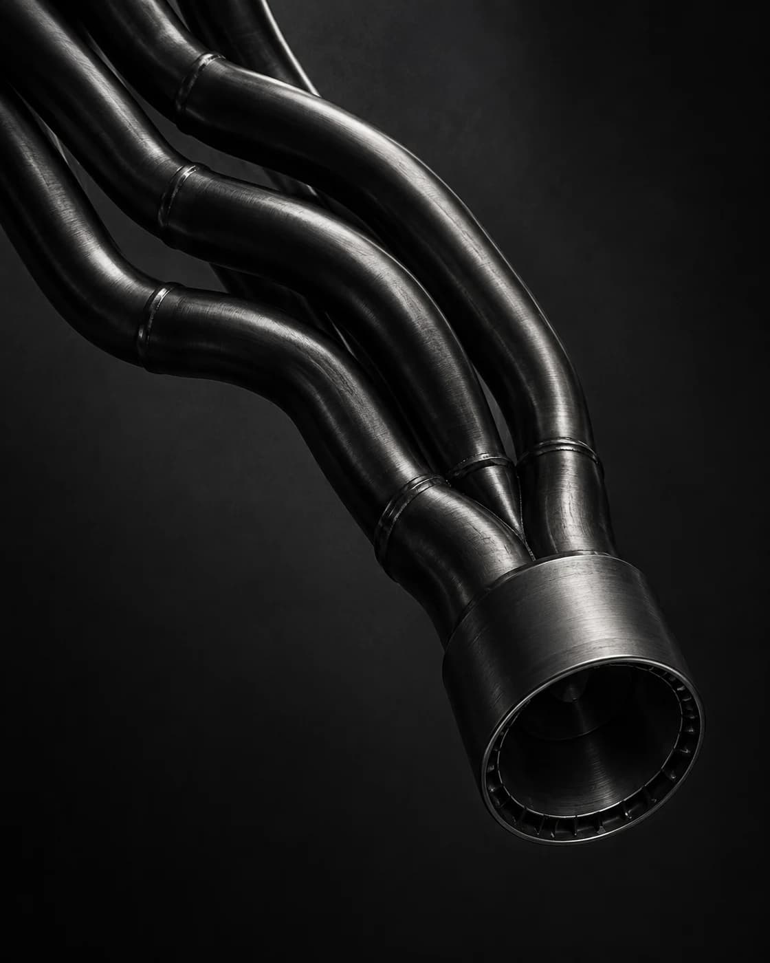 Four dark metal conduits curving diagonally into a single industrial socket.