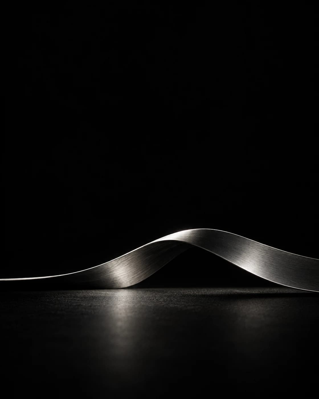 A silver ribbon bending across the lower third of a deep black scene.